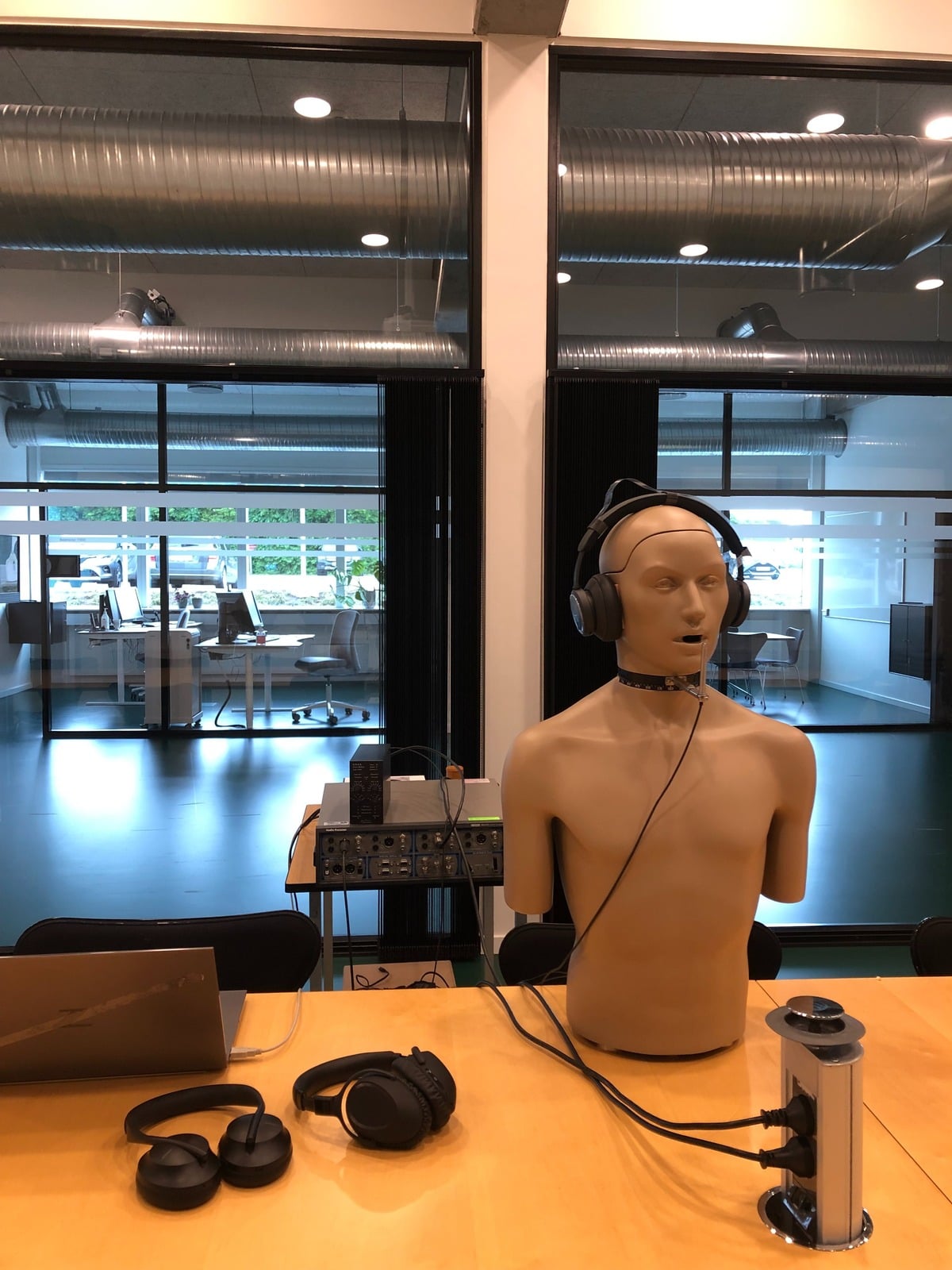 Head and torso simulator mannequin wired to audio test equipment